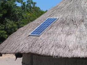 Eine Hütte mit Strohdach, auf dem Sonnenkollektoren angebracht sind.
