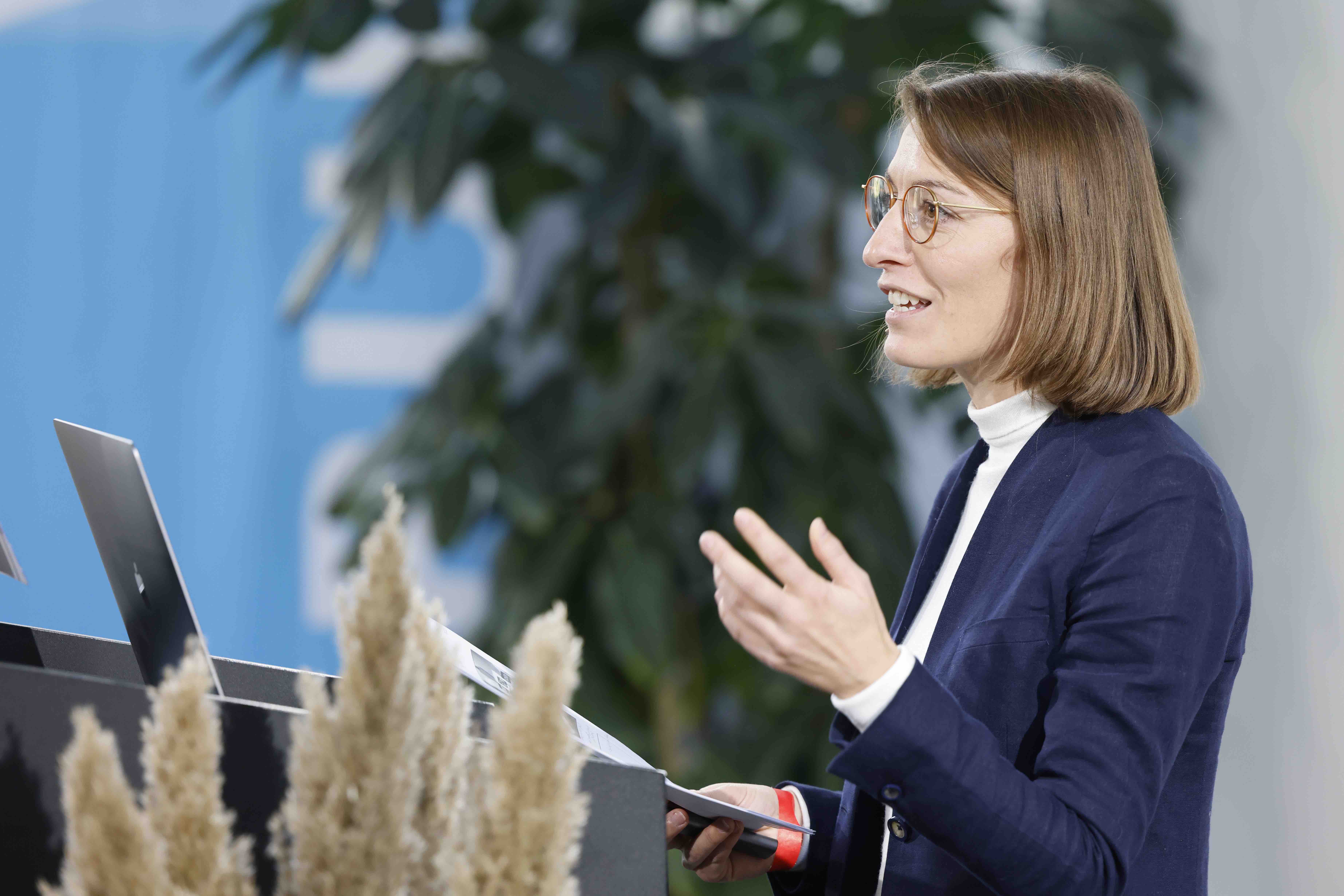 Die Referentin Dr. Lea Stahel vom Soziologischen Institut der Universität Zürich während ihrem Referat. Sie steht hinter einem Rednerpult mit einem Laptop und gestikuliert mit den Händen.