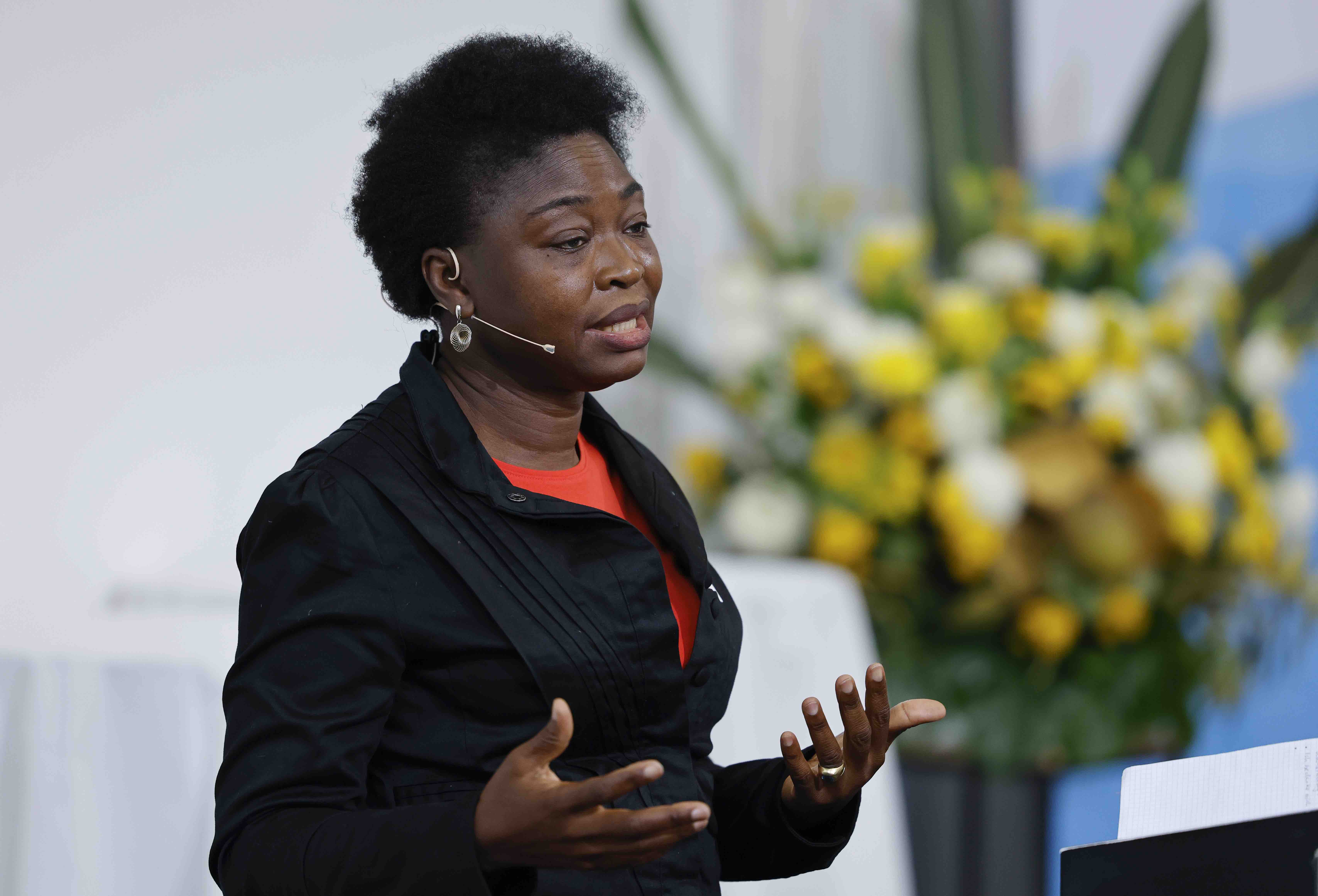 Porträtaufnahme von der Geographieprofessorin Chinwe Ifejika Speranza während ihrem Referat. Im Hintergrund ist ein Blumenstrauss zu sehen.