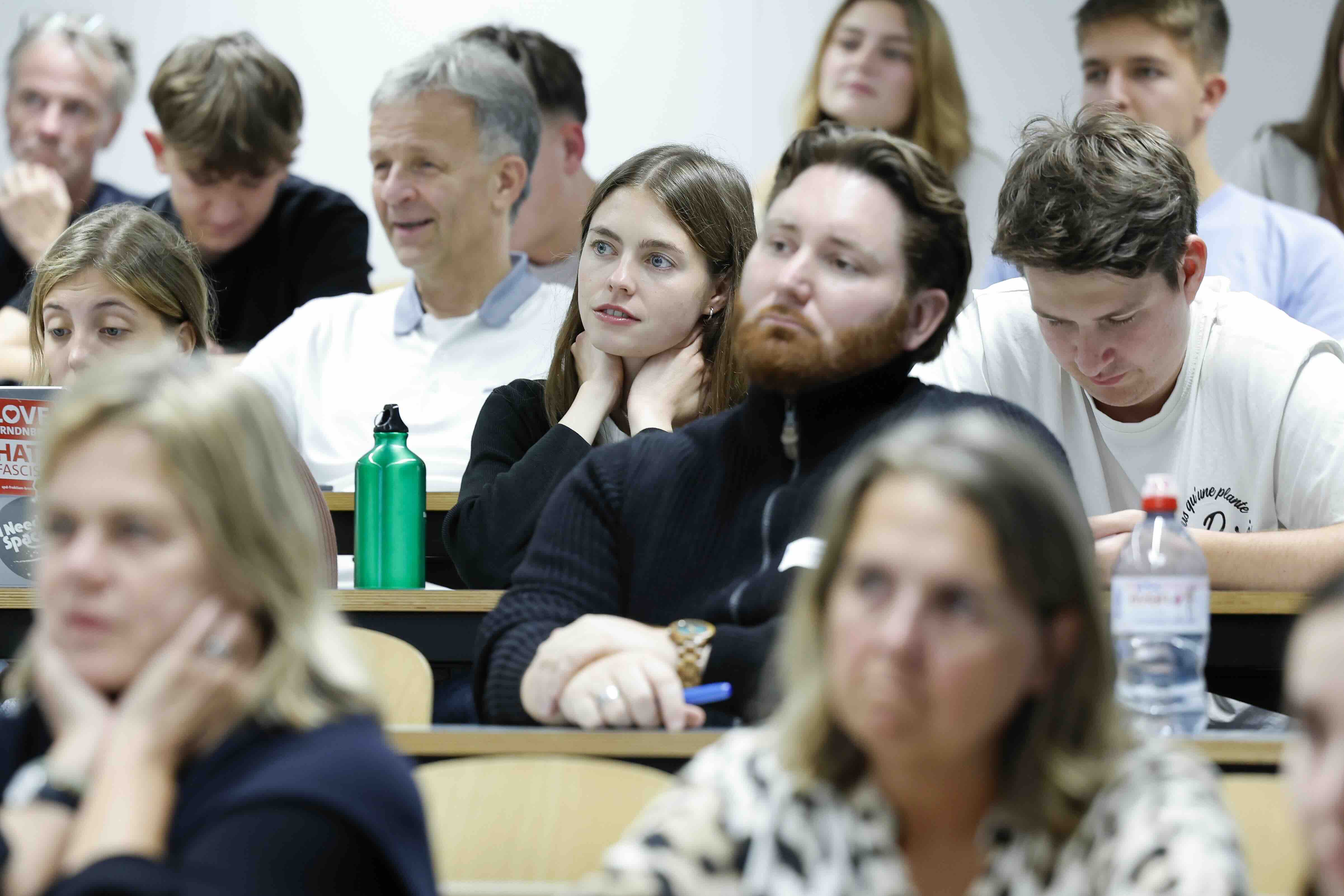 Publikum in einem Hörsaal der Universität Bern: Frauen und Männer unterschiedlichen Alters hören aufmerksam einem Vortrag zu.