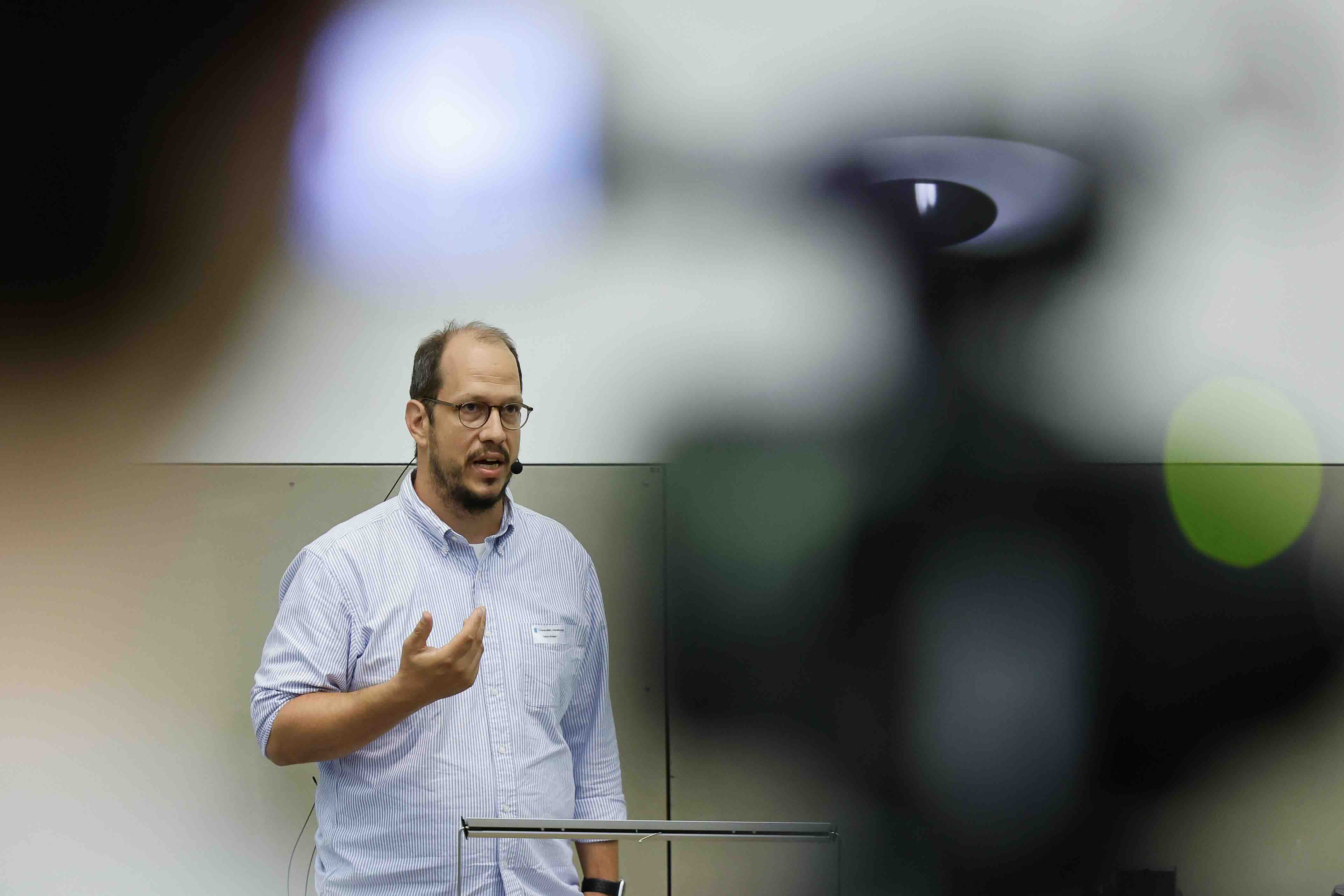 Tobias Krieger referiert mit Mikrofon zur psychischen Belastung durch Einsamkeit.