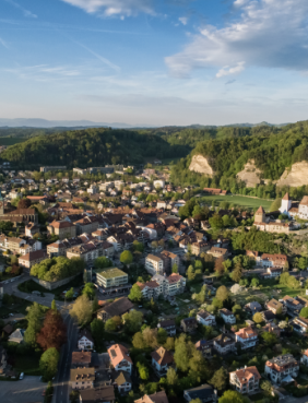 Luftaufnahme der Stadt Burgdorf im Kanton Bern mit Altstadt, Wohnquartieren, grünen Hügeln und markanten Sandsteinfelsen.