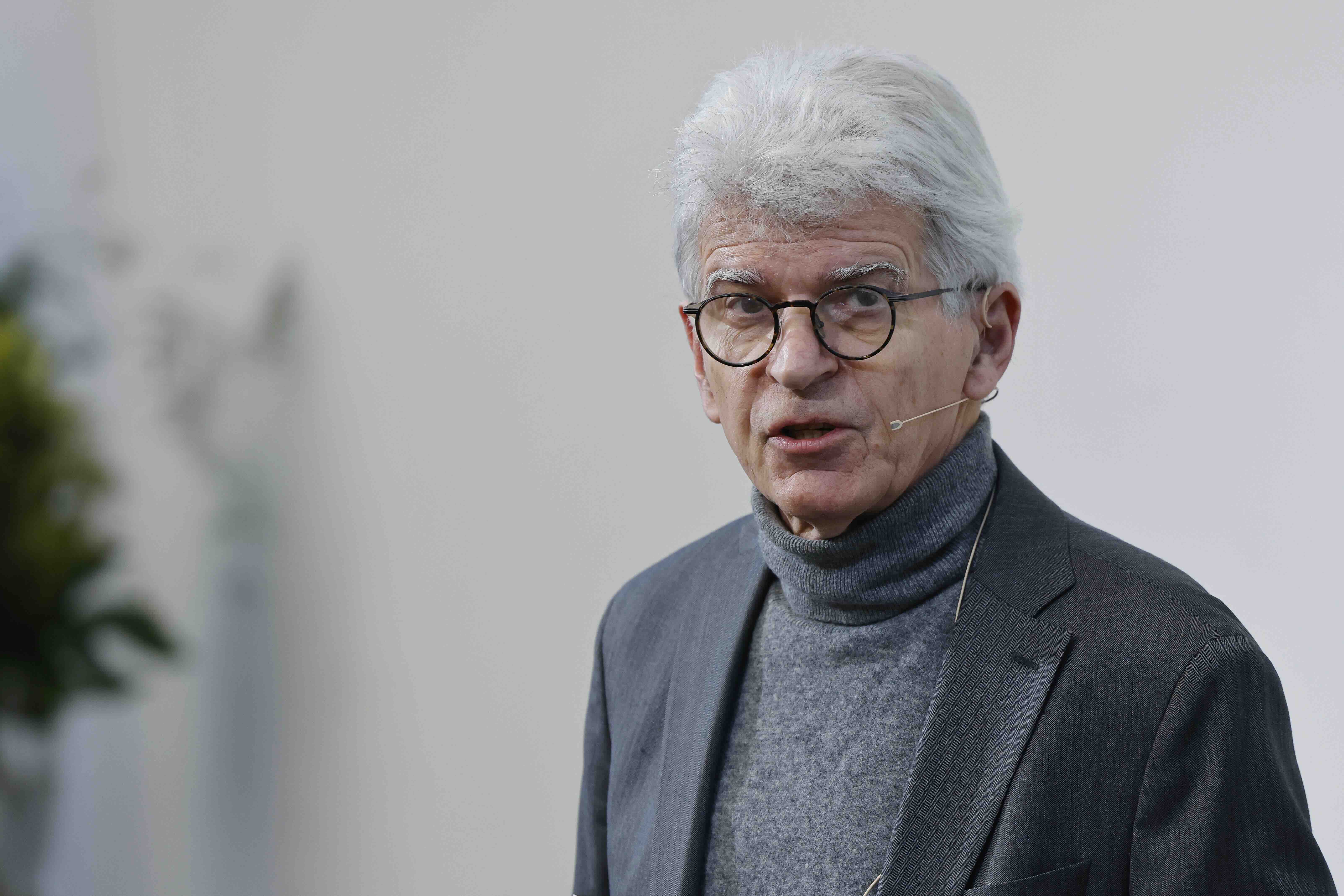 Ein Mann in grauem Anzug und mit Brille ist am sprechen.