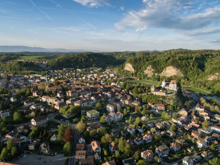 Luftaufnahme der Stadt Burgdorf im Kanton Bern mit Altstadt, Wohnquartieren, grünen Hügeln und markanten Sandsteinfelsen.