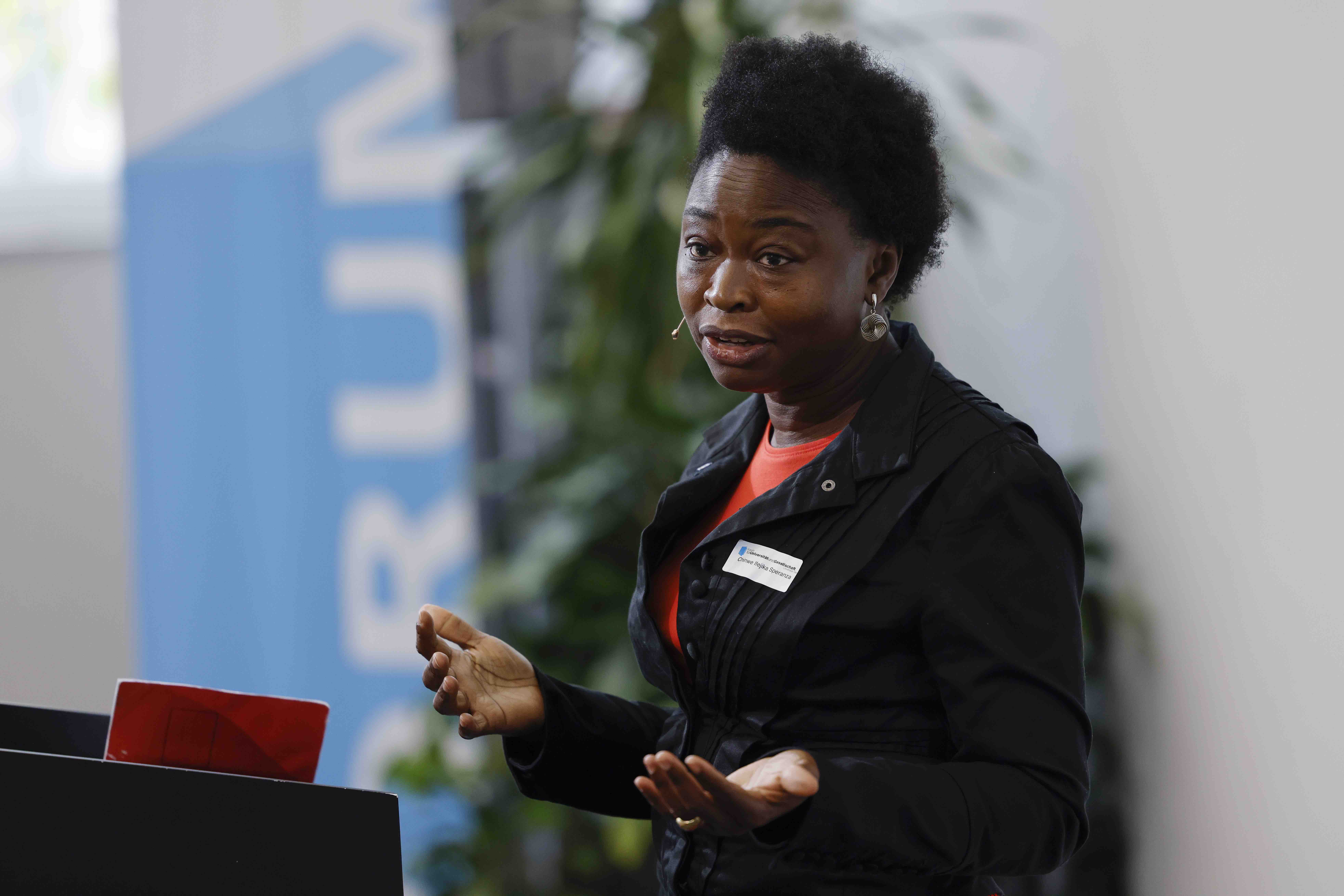 Porträtaufnahme von der Geographieprofessorin Chinwe Ifejika Speranza während ihrem Referat. Im Hintergrund ist ein Banner mit dem blauweissen Forumslogo zu sehen.